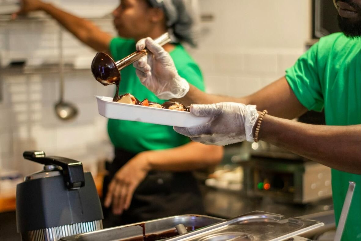 Restaurant staff in gloves plating a dessert for an order